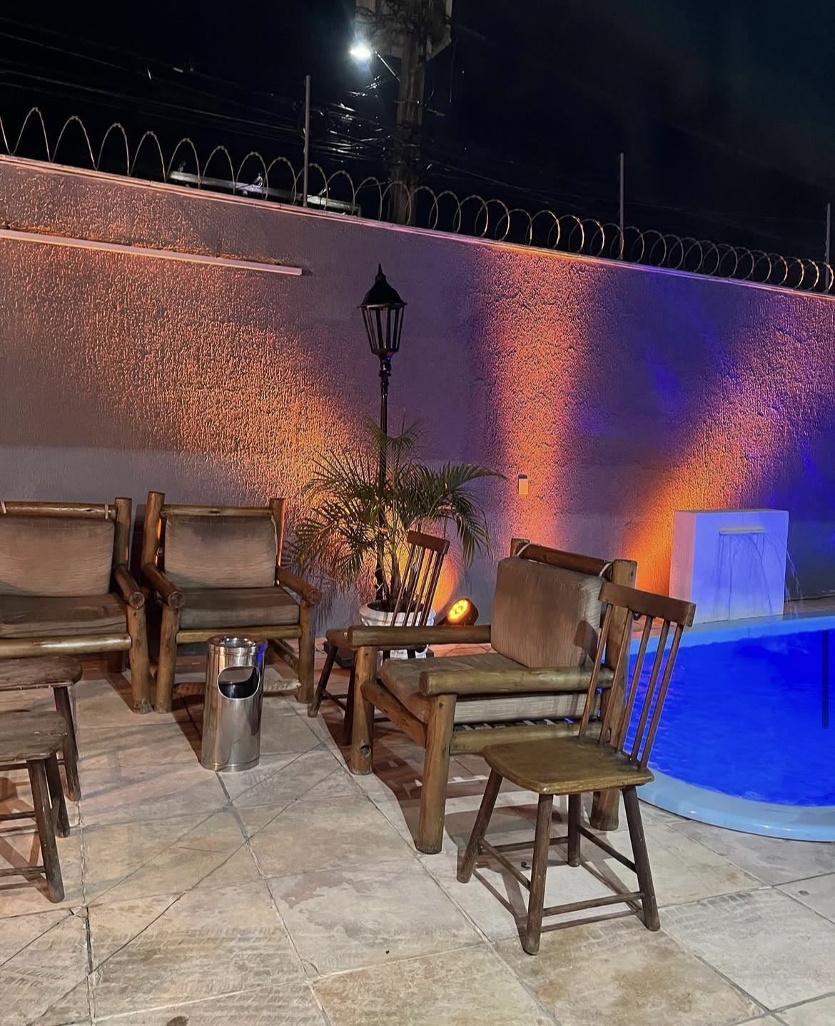 Área da piscina com cadeiras à noite